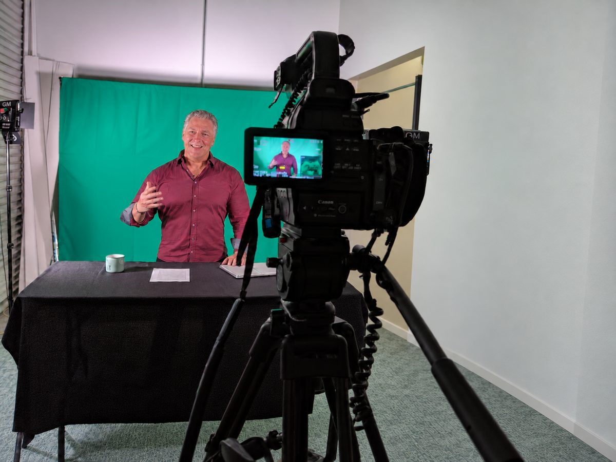 Sean Purcell recording a video in a studio, seen over the shoulder of the camera